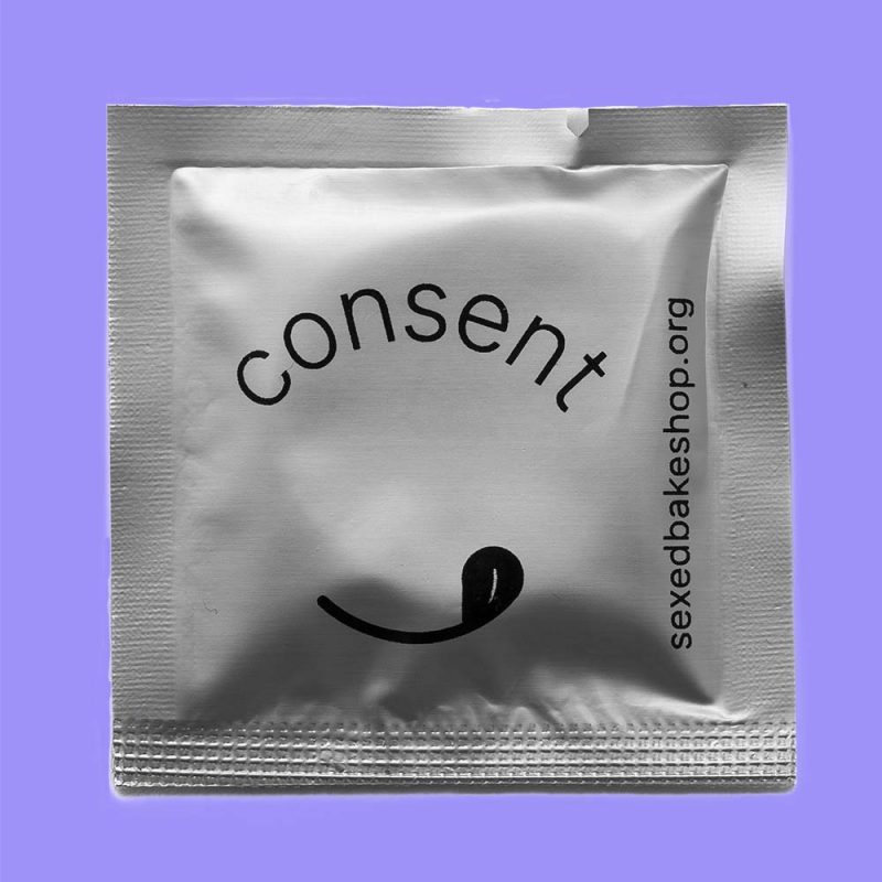 Silver condom wrapper with text 'consent' on a purple background.